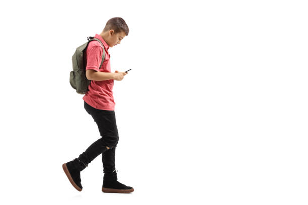 istock Trendy schoolboy walking and looking at a mobile phone 1077703234