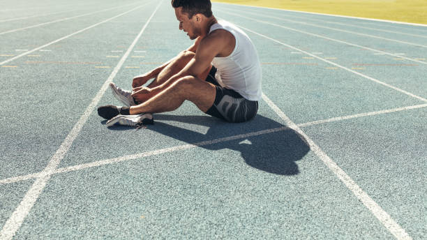 istock Sprinter tying shoe lace sitting on running track 1077706296