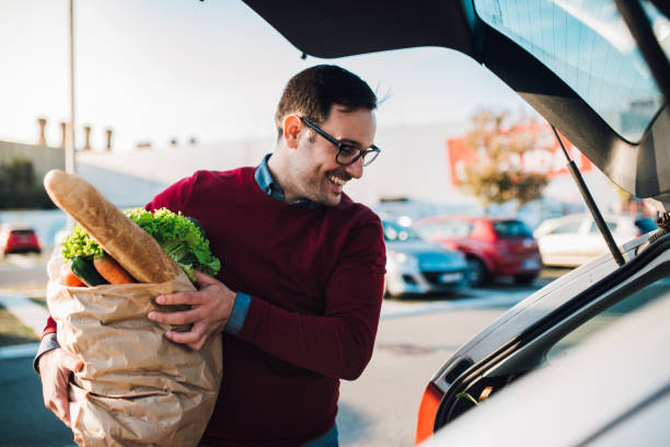 istock Young man putting groceries in a car 1077711812