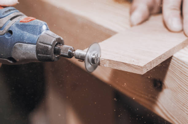 istock hands of a man holding a Dremel tool with an installed small circular saw. Wood processing. Workshop. Manufacture of wooden products. Joiner's cutting tool 1077714258