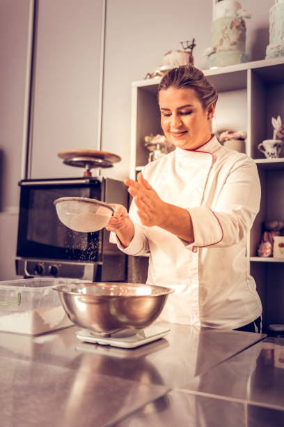 istock Delighted nice skilled woman sifting the flour 1077719280