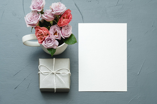 empty white paper with goft box and flower bouquet. greeting card mockup. womens day congratulation