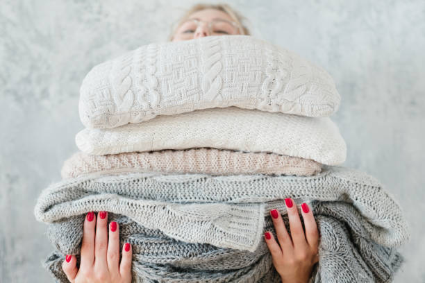 woman knitted plaid blanket cozy winter home decor woman holding big stack of knitted plaids and blankets. cozy and warm winter home decor jersey fabric photos stock pictures, royalty-free photos & images