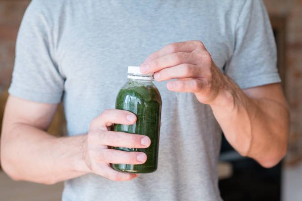 hombre mantener la salud de bebida de desintoxicación de batido verde botella - green drink fotografías e imágenes de stock