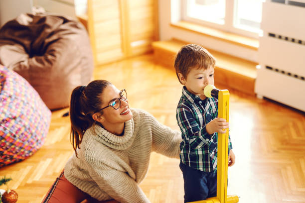 istock Cute little kid playing with toys while his mom holding him. 1077729992