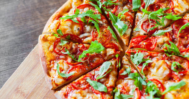 istock vegetarian Pizza with Mozzarella cheese, Tomatoes, pepper, Spices and Fresh arugula. Italian pizza. Pizza Margherita or Margarita on wooden table background 1077731216