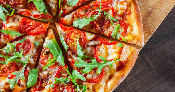 istock vegetarian Pizza with Mozzarella cheese, Tomatoes, pepper, Spices and Fresh arugula. Italian pizza. Pizza Margherita or Margarita on wooden table background 1077732334