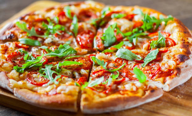 istock vegetarian Pizza with Mozzarella cheese, Tomatoes, pepper, Spices and Fresh arugula. Italian pizza. Pizza Margherita or Margarita on wooden table background 1077732346