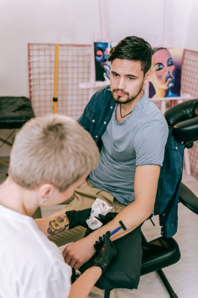 istock Calm client sitting on chair while master shaving his hand 1077741054