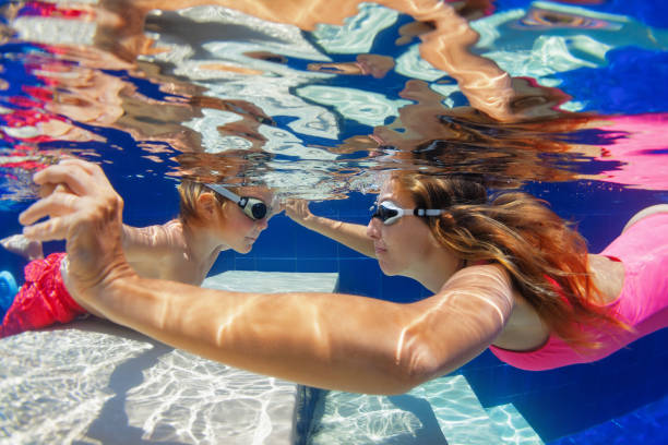 istock Child with mother dive in swimming pool 1077741150