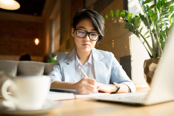 istock Pensive businesswoman in glasses making notes 1077743154