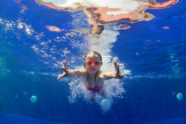 istock Funny child in goggles dive in swimming pool 1077743642