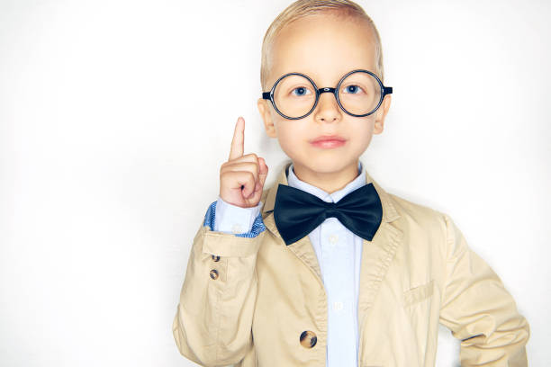 istock Cute little boy wearing a bowtie and glasses point upwards 1077743992