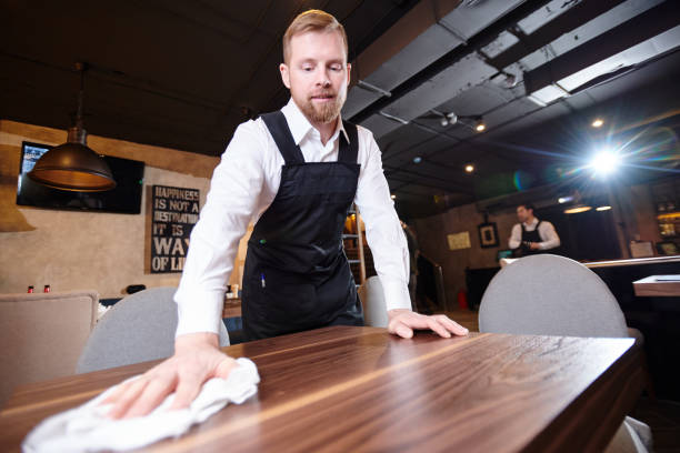 istock Handsome young waiter cleaning table in restaurant 1077746422