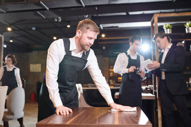 Bearded waiter wiping table in restaurant
