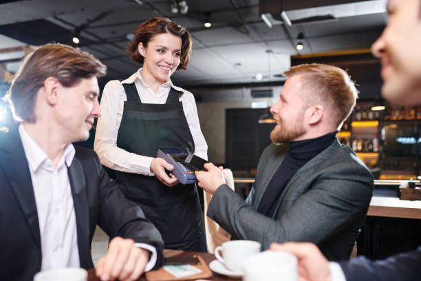 istock Pretty waitress giving terminal for payment to businessman 1077746484