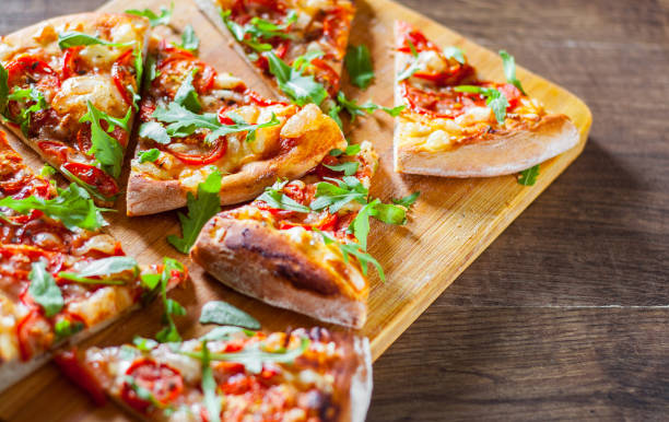 istock slices vegetarian Pizza with Mozzarella cheese, Tomatoes, pepper, Spices and Fresh arugula. Italian pizza. Pizza Margherita or Margarita on wooden table background 1077747870