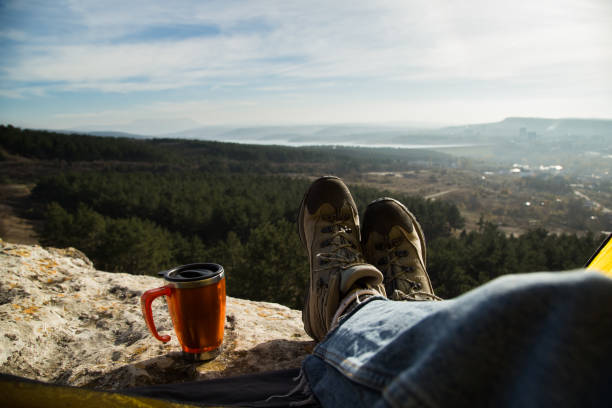 istock Hiking boots and a mug on a background of nature 1077750126