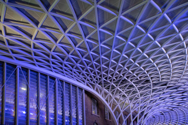 Kings Cross and St Pancras concourse ceiling at night with columns and patterns illuminated in purple light.