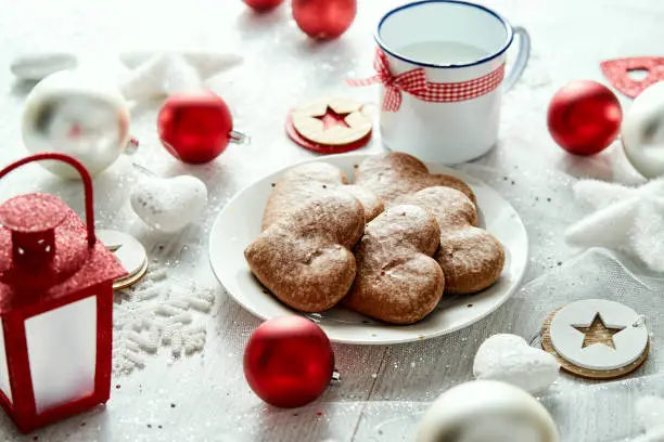 Christmas plate with homemade gingerbreads snowflakes baubles and red lantern on a silver-plated table