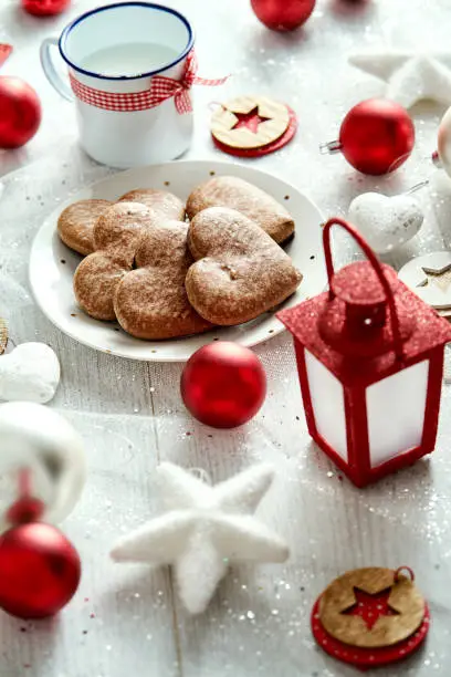 Christmas plate with homemade gingerbreads snowflakes baubles and red lantern on a silver-plated table.