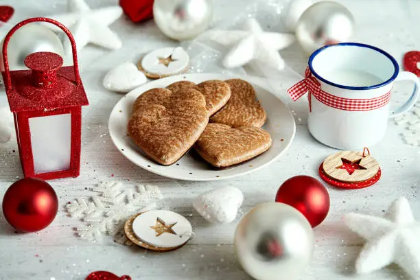 Christmas plate with homemade gingerbreads snowflakes baubles and red lantern on a silver-plated table.