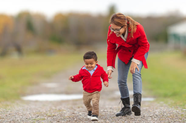 madre e bambino che prendono i primi passi all'esterno - baby first steps autumn child foto e immagini stock