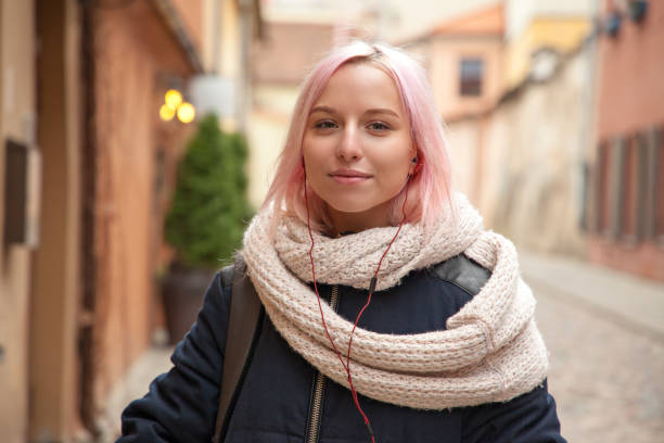 Portrait of 18 year old woman on a city street Portrait of 18 year old woman with pink hair and headphones on city street pink hair stock pictures, royalty-free photos & images