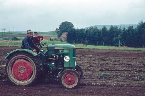 The farmer orders his field in spring Schönsee, Schwandorf, Bavaria, Germany, 1961. A farmer orders a field with his tractor. His two sons ride with him. agricultural machinery photos stock pictures, royalty-free photos & images