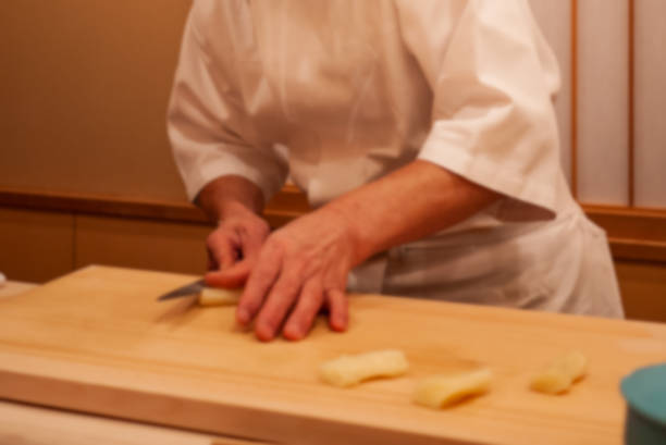 istock Blurred. Motion. Professional sushi chef uses sharp knife to slice carefully to make perfect sushi with precision. 1077786492