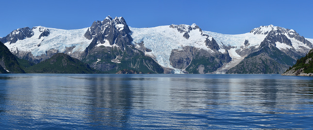View of the the Anchor Glacier (in the middle) and Ogilvie Glacier (right) located in Kenai Fjords National Park, Kenai Peninsula, Alaska. This glaciers are retreating, proving global warming. Picture taken in June on unusually sunny day from a boat cruising the Harris Bay and Northwestern Fjord out of Seward, Alaska.