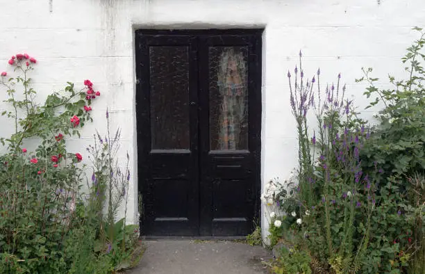 A double door entry with surrounding plants against a white block wall.