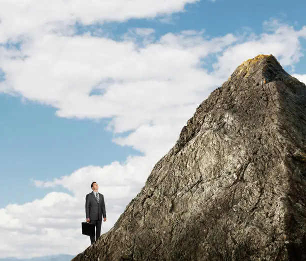 Photo of Businessman Looking Up At Mountain Peak