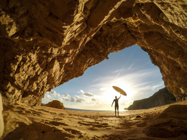 surfer holding a surfboard up into the sun - surfing sport extreme sports success imagens e fotografias de stock