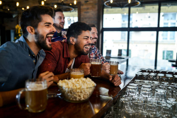 istock Group of young joyful friends having fun while toasting with beer in a pub 1077800390
