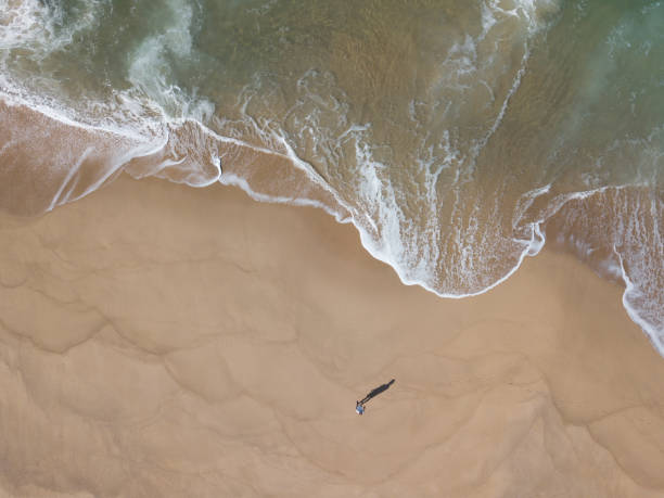 Man and shadow on sand beach from above stock photo