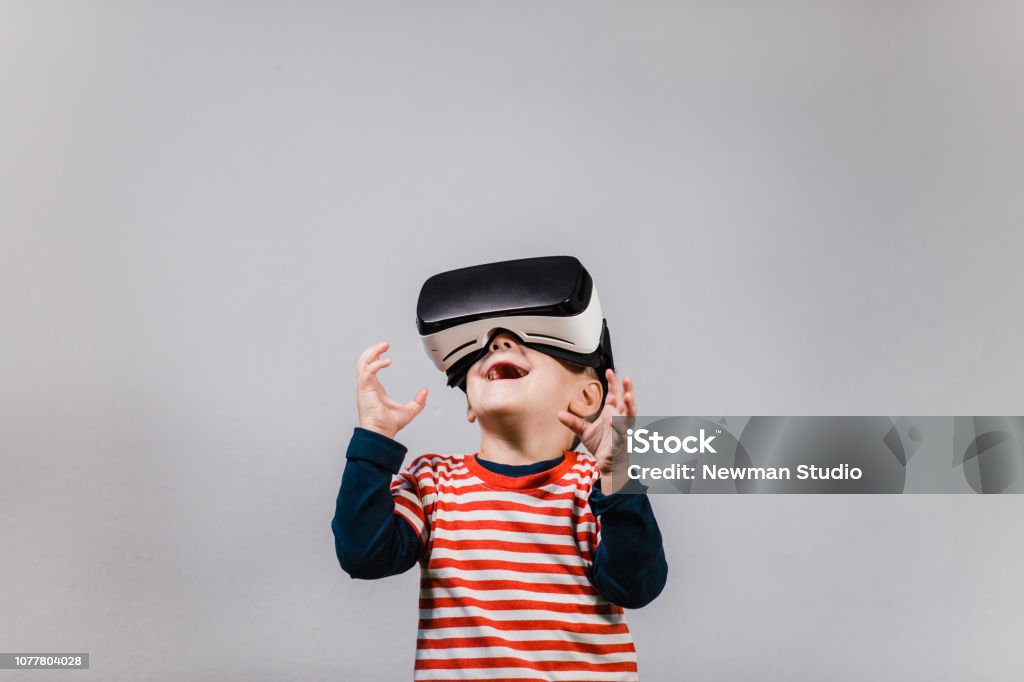 Ragazzo eccitato che si diverte con gli occhiali VR. - Foto stock royalty-free di Simulatore di realtà virtuale