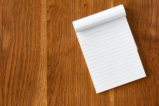Top view of blank open notebook page with lines on dark wooden background with copy space. For use as mock up