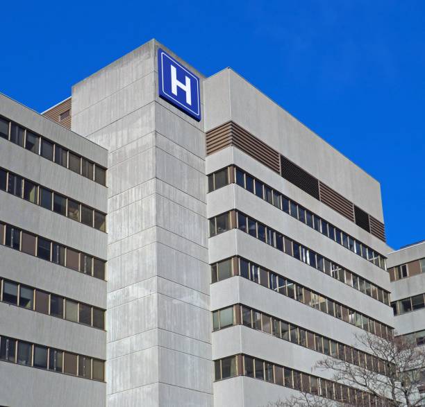 istock Large concrete building with  H sign for hospital 1077806922