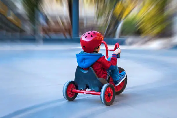 Boy with a helmet ridding a red tricycle