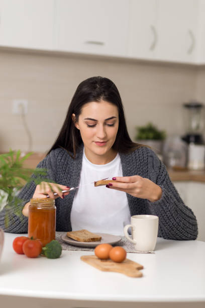 istock Young woman spreading jam on a slice of bread 1077813040