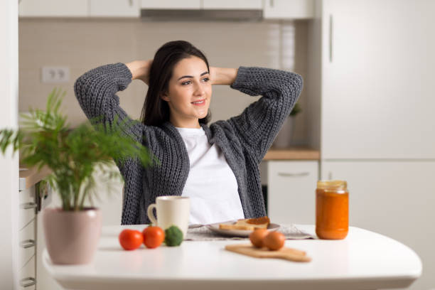 Young woman stretching during breakfast time at home