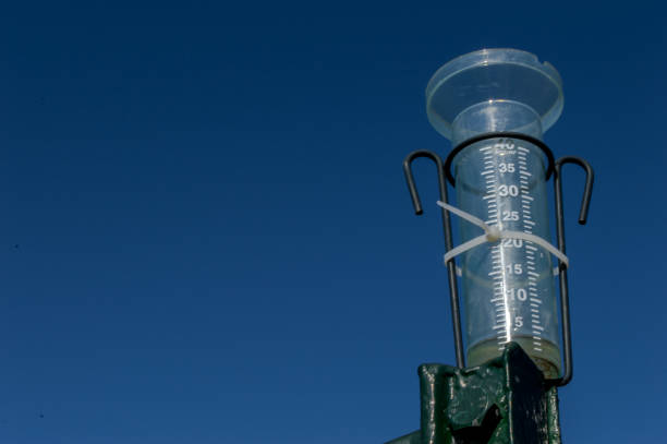 Pluviometer or rain gauge on a clear blue sky background with some rainwater. Instrument used in meteorology to calculate the amount of rain per cubic meter. Pluviometer or rain gauge on a clear blue sky background with some rainwater. Instrument used in meteorology to calculate the amount of rain per cubic meter. rain gauge stock pictures, royalty-free photos & images