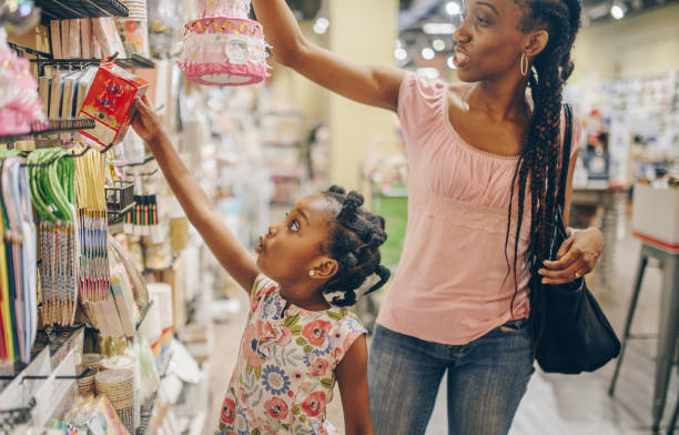 Shopping with Mom Woman and Child, little girl, 4 years old, African American mother and daughter, browse a shop, candid, happy, light and bright, they are enjoying time and shopping together toy store stock pictures, royalty-free photos & images