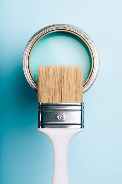 istock Brush on open can of turquoise paint on blue pastel background. 1077835442