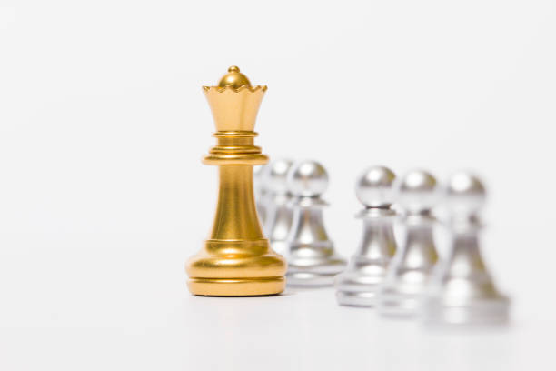 Black chess queen stands triumphantly over the fallen king of the defeated player, who has resigned.