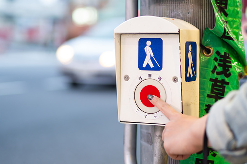 Pressing button for disabled person for crossing the road at the traffic light