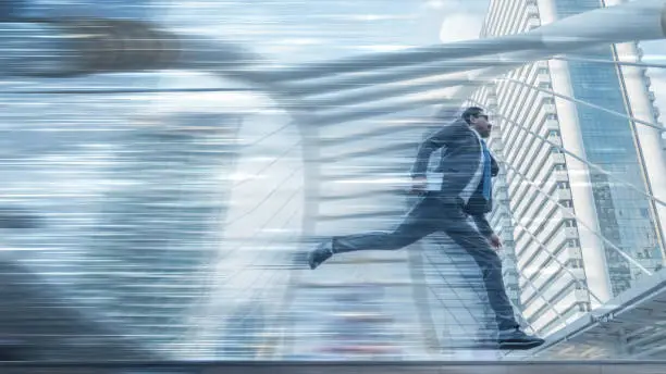 Photo of abstract motion blurred background of businessman with tablet on hand runing with speed motion trails and background of skyscrapers in city in conpept of running business at high speed
