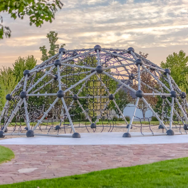 istock Dome climbing frame against trees homes and sky 1077872750