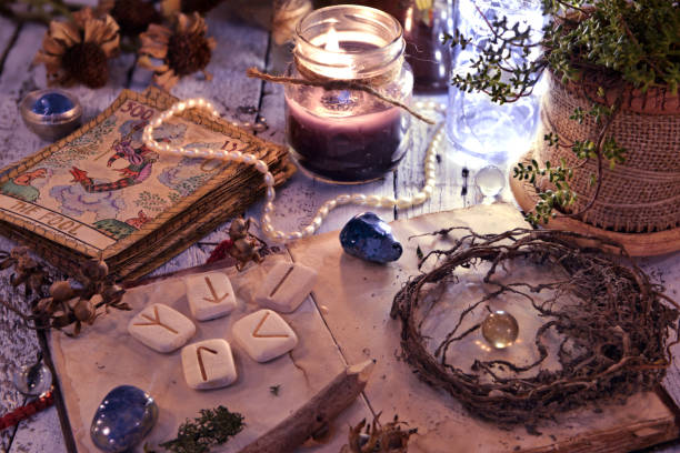 istock Old tarot cards deck, runes and dried roots with book on table 1077893420